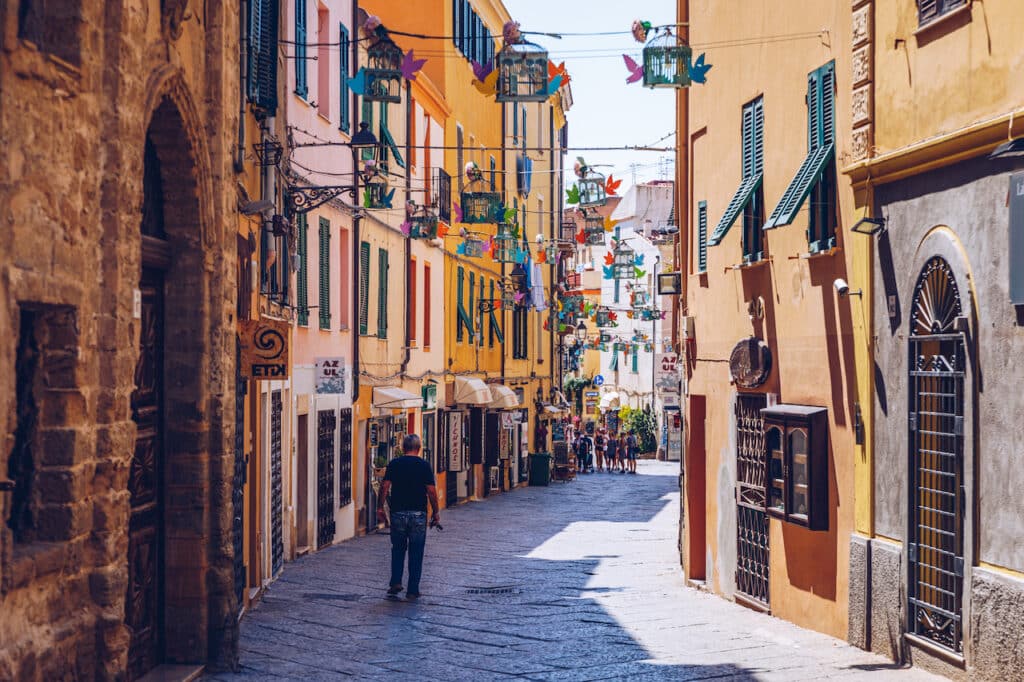Smal gate med fargerike hus og flagg i Alghero på Sardinia