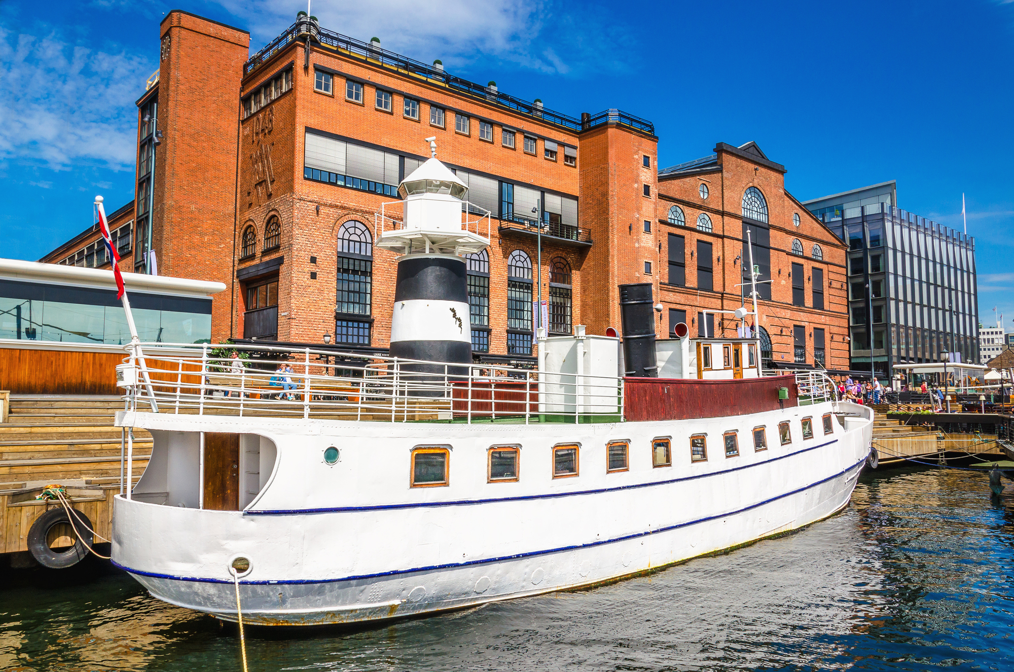 Aker Brygge i Oslo med en hvit yacht i havnen
