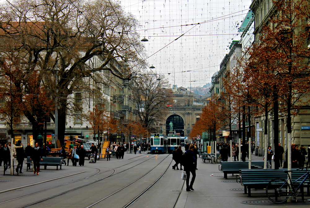 Bahnhofstrasse i Zürich med trikkeskinner og fotgjengere og sentralstasjonen i enden av gaten