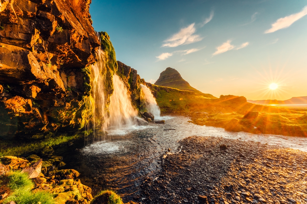 Fjellet Kirkjufell og fossen Kirkjufellsfoss på Snæfellsnes ved soloppgang