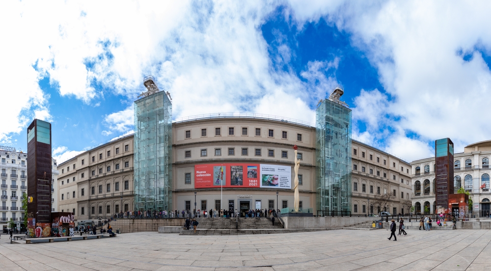 Hovedfasaden på Museo Reina Sofía i Madrid med besøkende i kø ved inngangen