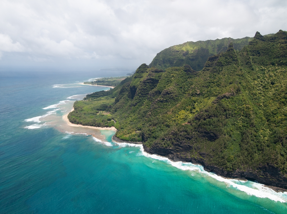 Flyfoto av Na Pali-kysten på Kauai med bratte grønne klipper og turkis hav