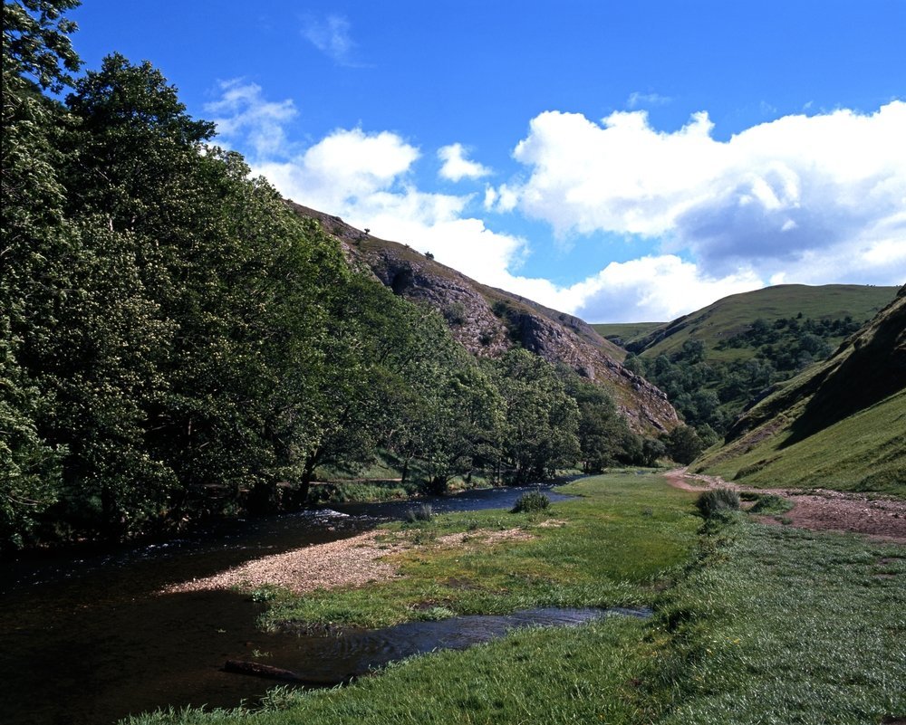 Elva Dove slynger seg gjennom kalksteinsdalen Dovedale nord for Ashbourne