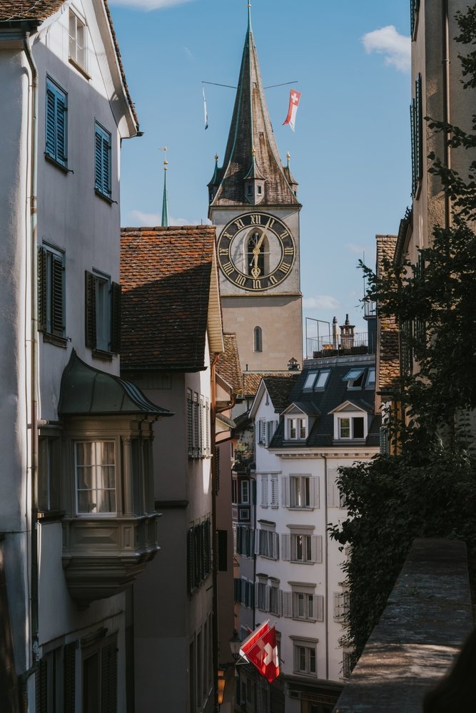 Gate i Niederdorf i Zürich med sveitsiske flagg og tårnet på St. Peter i bakgrunnen