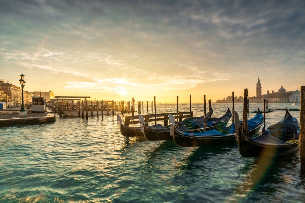 Gondoler fortøyd ved kaia i Venezia i solnedgang