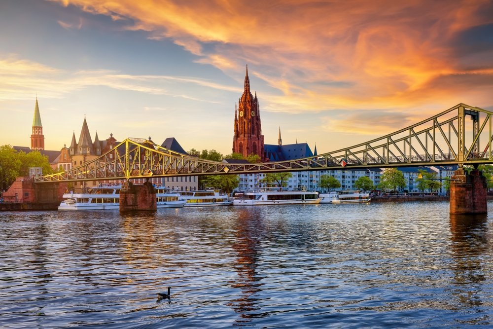 Frankfurts skyline med gangbroen Eiserner Steg og Keiserdomen over Main ved solnedgang