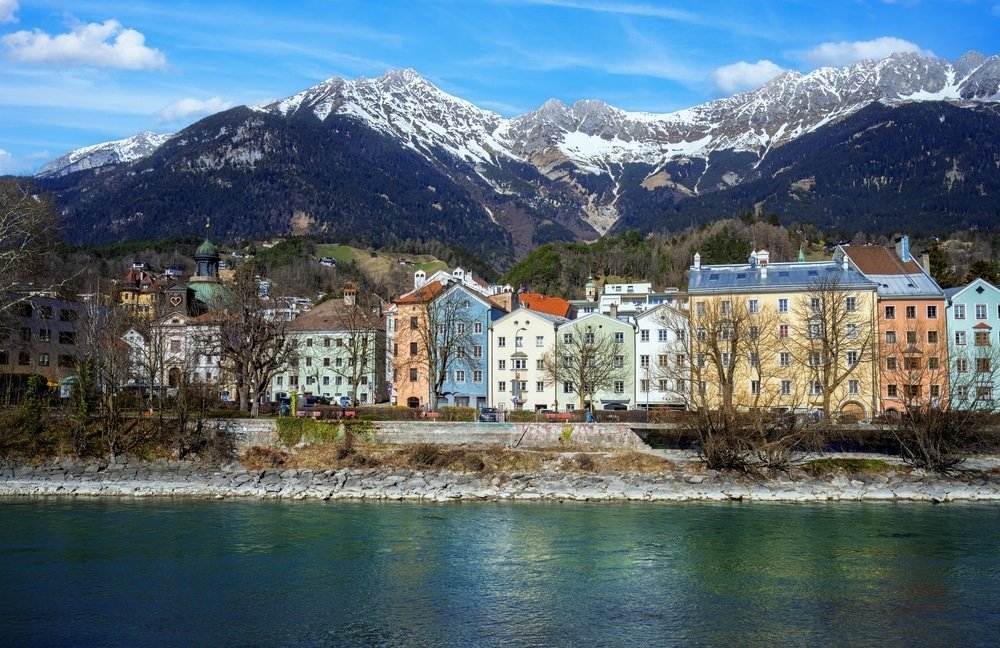Hvor skal man bo i Innsbruck: de fargerike husene langs elven Inn med Nordkette i bakgrunnen