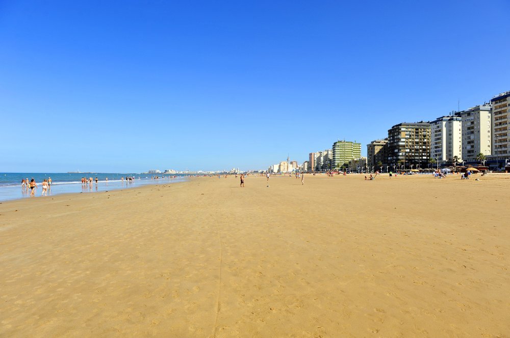 Den lange sandstranden Playa de la Victoria i Cádiz med strandpromenaden