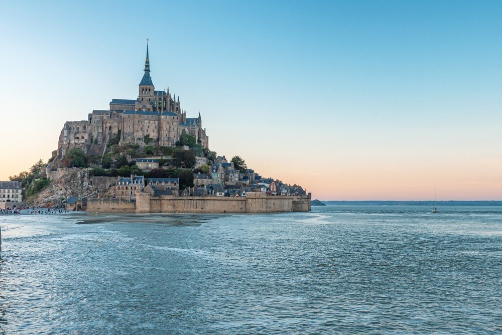 Mont-Saint-Michel omgitt av vann ved høyvann i solnedgang