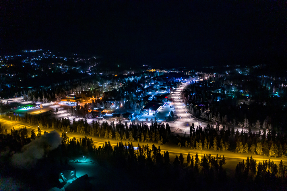 Flyfoto av Saariselkä om kvelden med fargerike lys i finsk Lappland