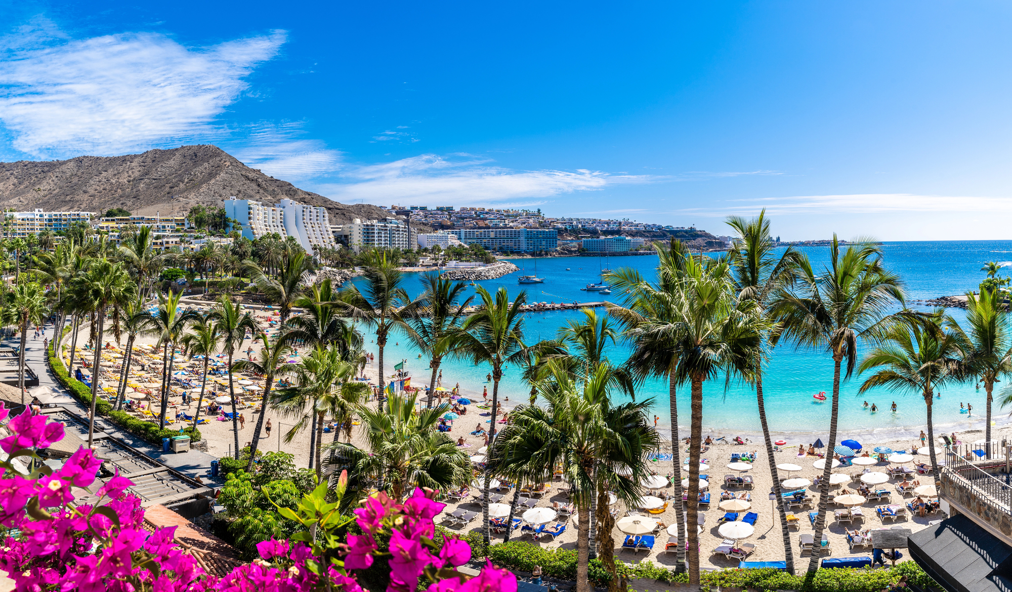 Stranden ved Anfi del Mar på Gran Canaria med palmer, parasoller og turkist vann