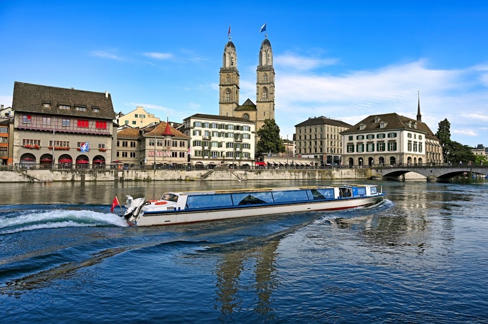 Turistbåt seiler på Limmat i Zürich med Grossmünster i bakgrunnen